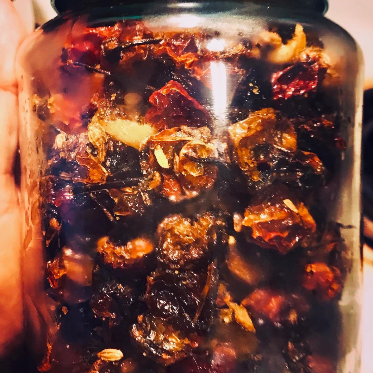 A glass jar packed with dark oily chili achar