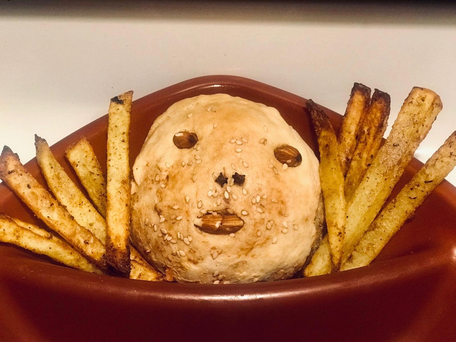 A round baked bread with a face made of almonds and cloves, surrounded by oven fries