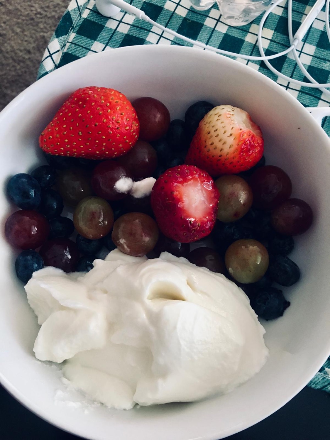 A bowl of thick yogurt with strawberries, grapes and blueberries