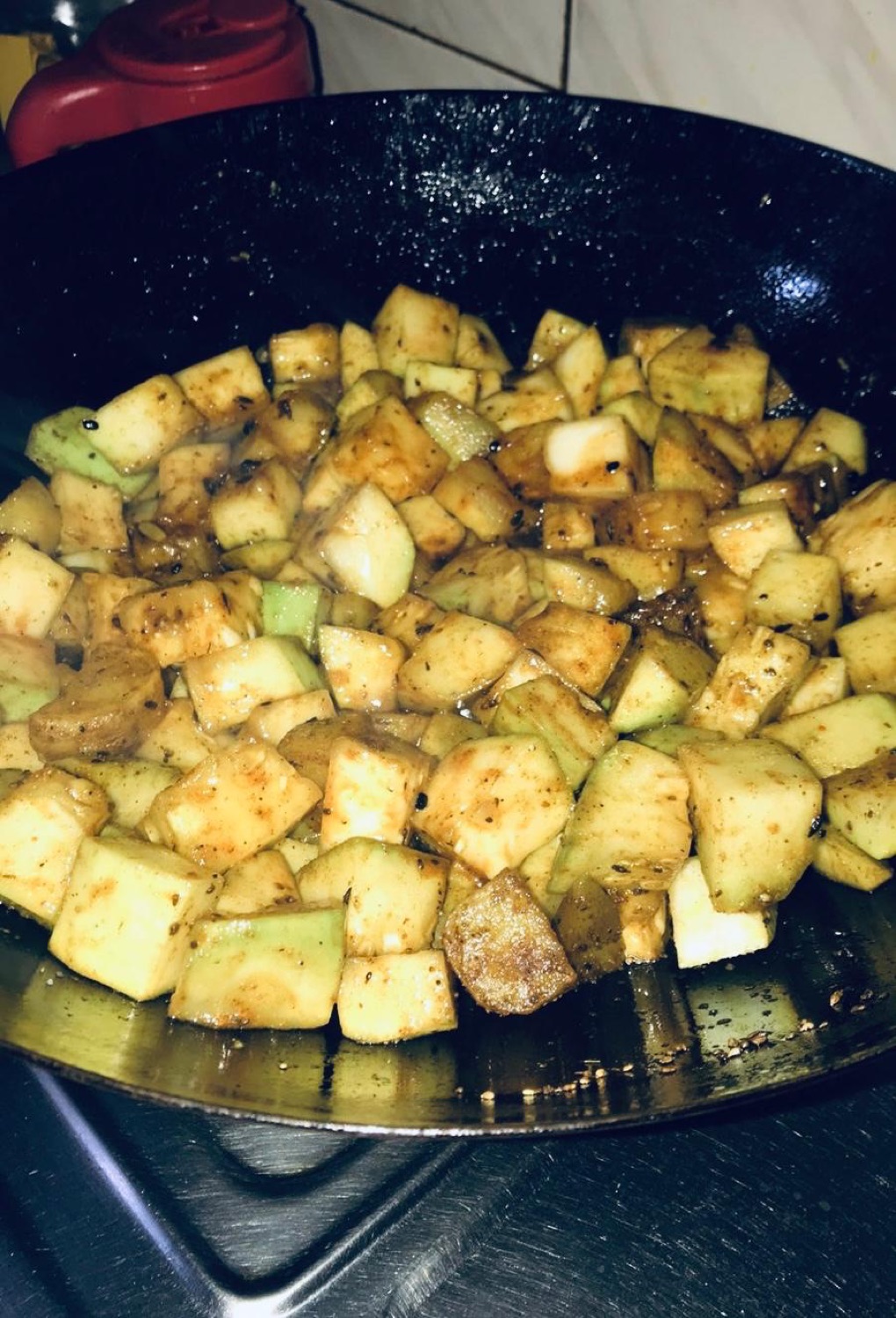 Cubed squash frying with spices in a black kadhai