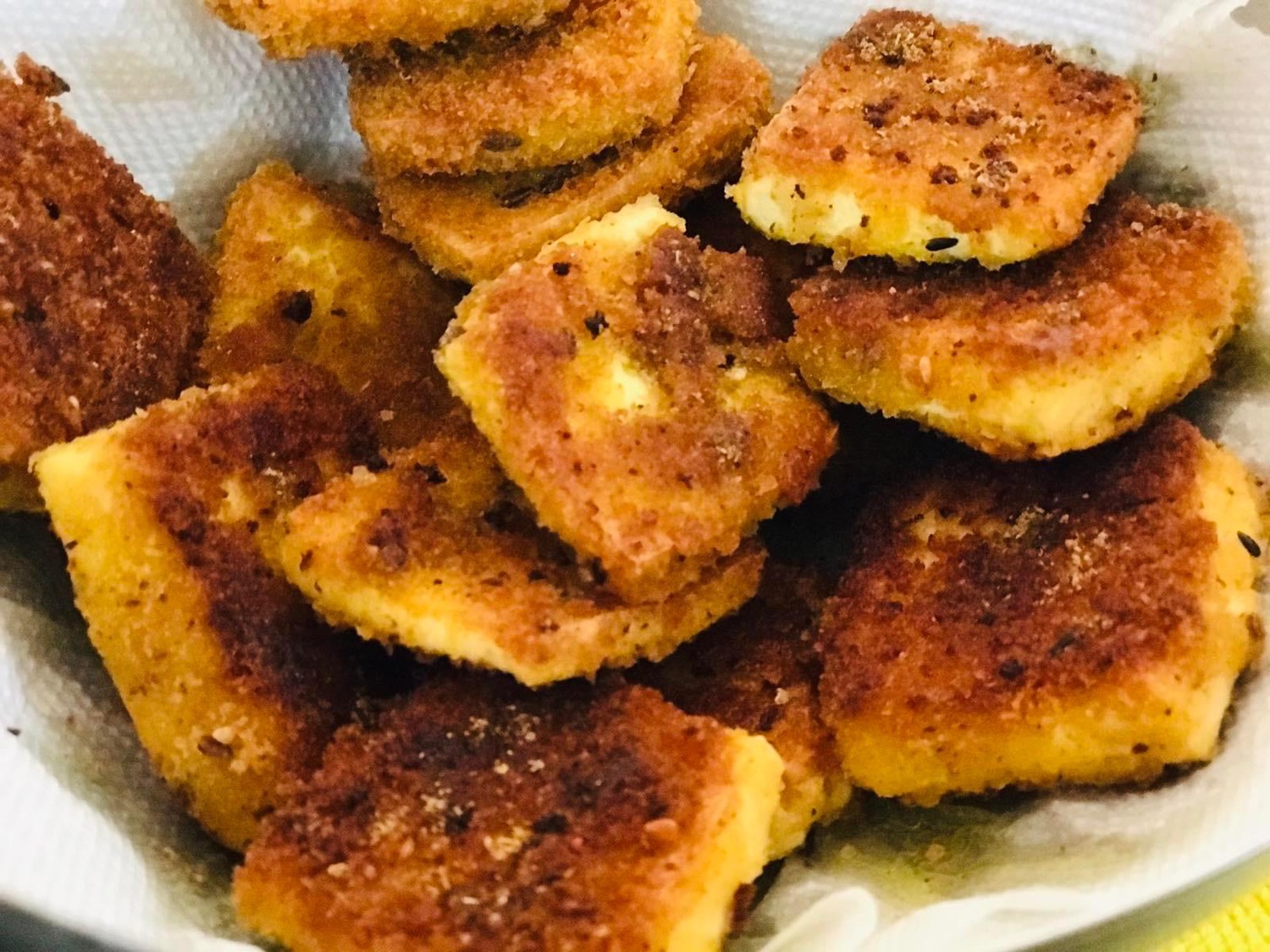 Golden crumbed and fried snack pieces resting on a paper towel